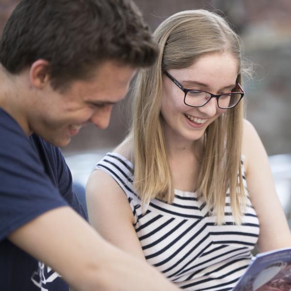 Teacher taking a look at a textbook with a student in the garden